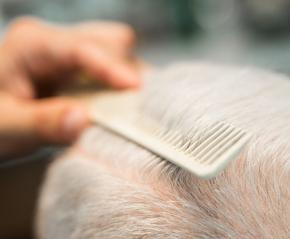 Un pettine passa fra i capelli grigi di un uomo